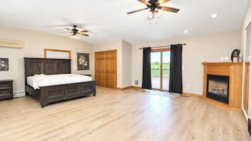 A spacious bedroom with a large bed, two ceiling fans, a fireplace, and a sliding glass door to a balcony.