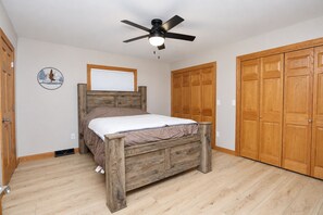 A bedroom with a wooden bed, a ceiling fan, and wooden wardrobes.