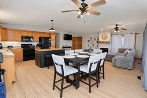 A modern kitchen with wooden cabinets, a central island, and a dining area with a round table and chairs.