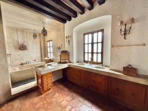 Une salle de bain avec une grande fenêtre, des meubles en bois, un miroir et un lavabo.