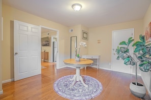 A hallway with a white door, a small table with a vase, and a potted plant. - Centrally Located Cozy Overton Square 83-R1 (Memphis)