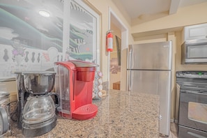 A kitchen with a coffee maker, a red appliance, and a stainless steel refrigerator. - Centrally Located Cozy Overton Square 83-R1 (Memphis)