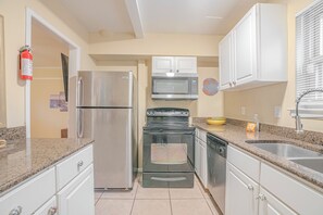 Una cocina con un refrigerador de acero inoxidable, un microondas, una estufa y un lavavajillas.