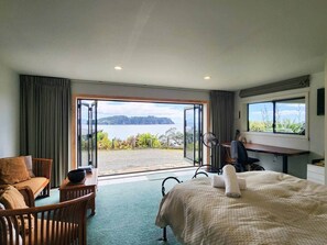Ein Hotelzimmer mit Bett, Schreibtisch, Stuhl, Meerblick und einem Balkon.
