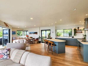 Eine moderne Küche mit Barbereich, Holzboden und großen Fenstern.