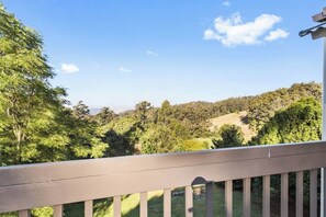 Um deck de madeira com vista para uma paisagem arborizada e montanhosa.