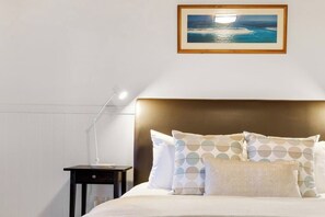 Ein Hotelzimmer mit Bett, Nachttisch, Lampe und einem gerahmten Bild an der Wand.