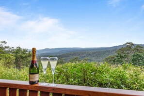 Een fles Moët & Chandon champagne en twee glazen op een houten leuning, met uitzicht op een bebost landschap.