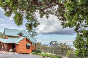 A wooden cabin with a green roof, surrounded by trees and a clear sky. - Quingilli Luxury Chalet 1 Bedroom (Ravensbourne)