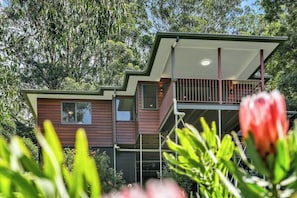 A modern two-story house with a balcony, surrounded by lush greenery. - Yume House Stylish Country Escape 1 Bedroom (Ravensbourne)