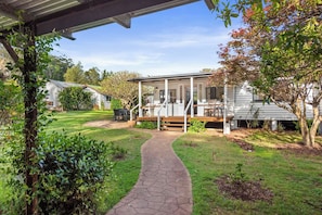 A house with a covered patio, a pathway leading to the entrance, and a lawn. - Mahali House - 4 Bedroom Holiday House (Ravensbourne)