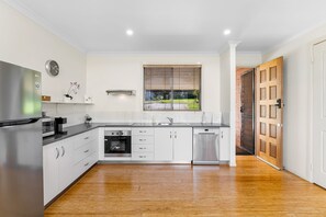 A modern kitchen with white cabinetry, stainless steel appliances, and a wooden floor. - Stella Luna - Luxury Chalet 1 Bedroom (Ravensbourne)