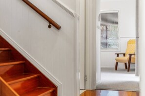 A wooden staircase leading to a room with a window and a chair.