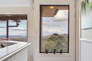 A room with a large window offering a scenic view of a forested mountain range.