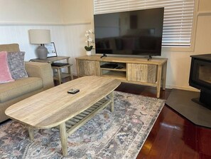 A living room with a sofa, coffee table, TV stand, and fireplace.