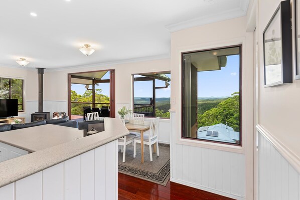 A modern kitchen with a central island, white cabinetry, and a large window offering a view of the outdoors.