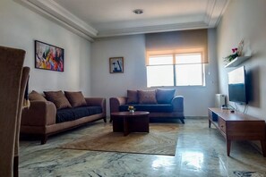 A living room with two sofas, a coffee table, a TV, and artwork on the walls. - Urban Flat near Lake (Tunis)