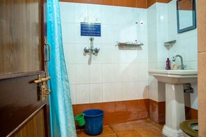 A bathroom with a shower, sink, and toilet. There is a sign indicating hot and cold water taps. - Hotel Lake Ghat Palace (Udaipur)