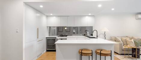 Een moderne keuken met witte kastjes, een centraal eiland en twee krukken.