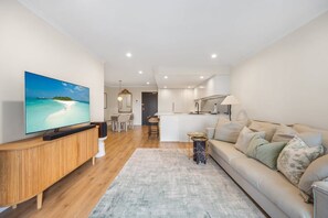 A modern living room with a flat-screen TV, a wooden console, a grey rug, and a beige sofa. - BOWIE - Pyrmont Paradise | Leafy Balcony With City Glimpses (Pyrmont)
