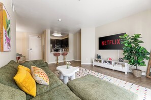 A modern living room with a green sofa, a white coffee table, and a colorful rug. - Charming 2-bedroom apartment with pool, gym and free parking in Marina del Rey! (Marina del Rey)
