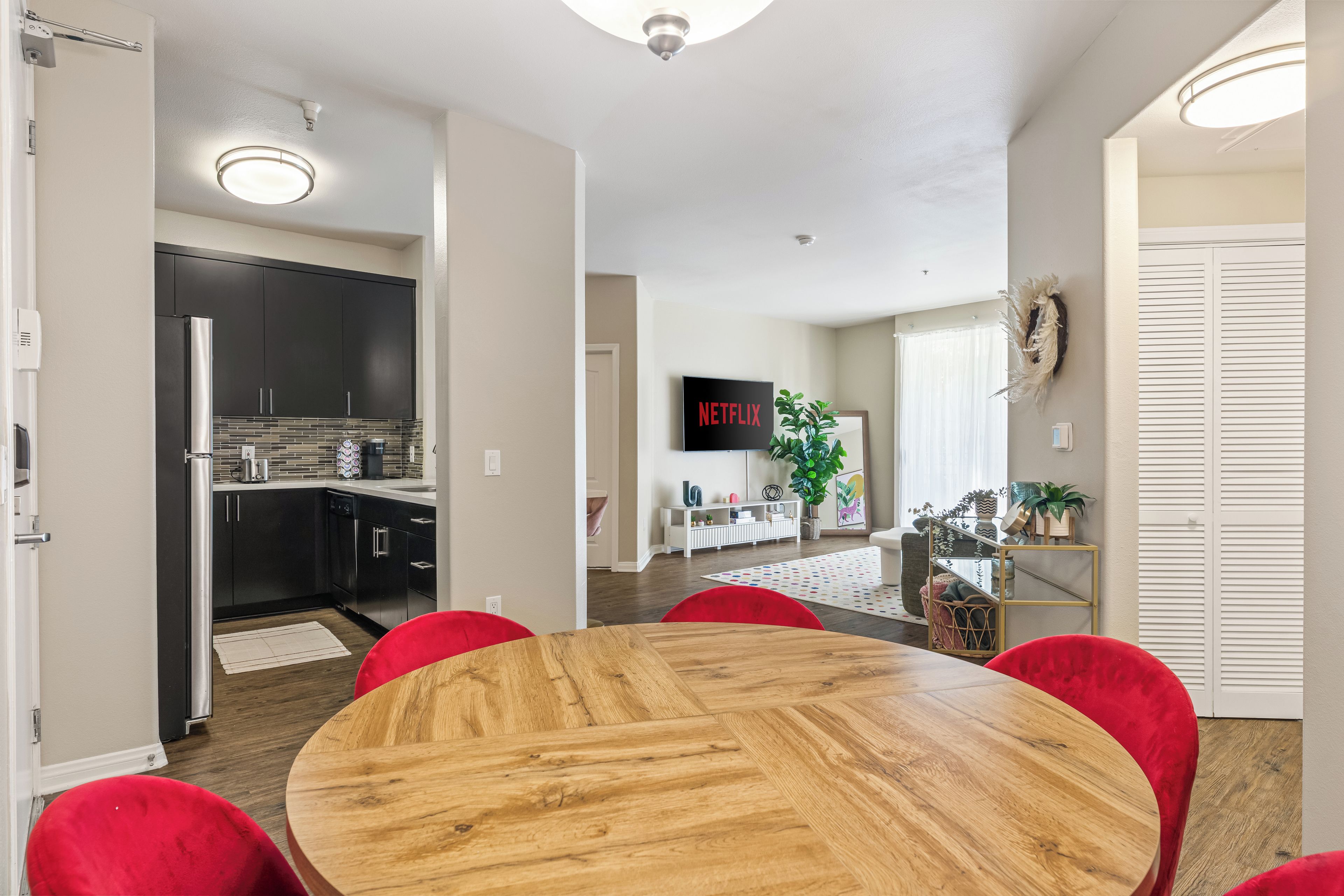 A modern kitchen with dark cabinets, a stainless steel refrigerator, and a tiled backsplash.