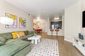 A modern living room with a green sofa, a white coffee table, and a colorful polka dot rug. - Charming 2-bedroom apartment with pool, gym and free parking in Marina del Rey! (Marina del Rey)