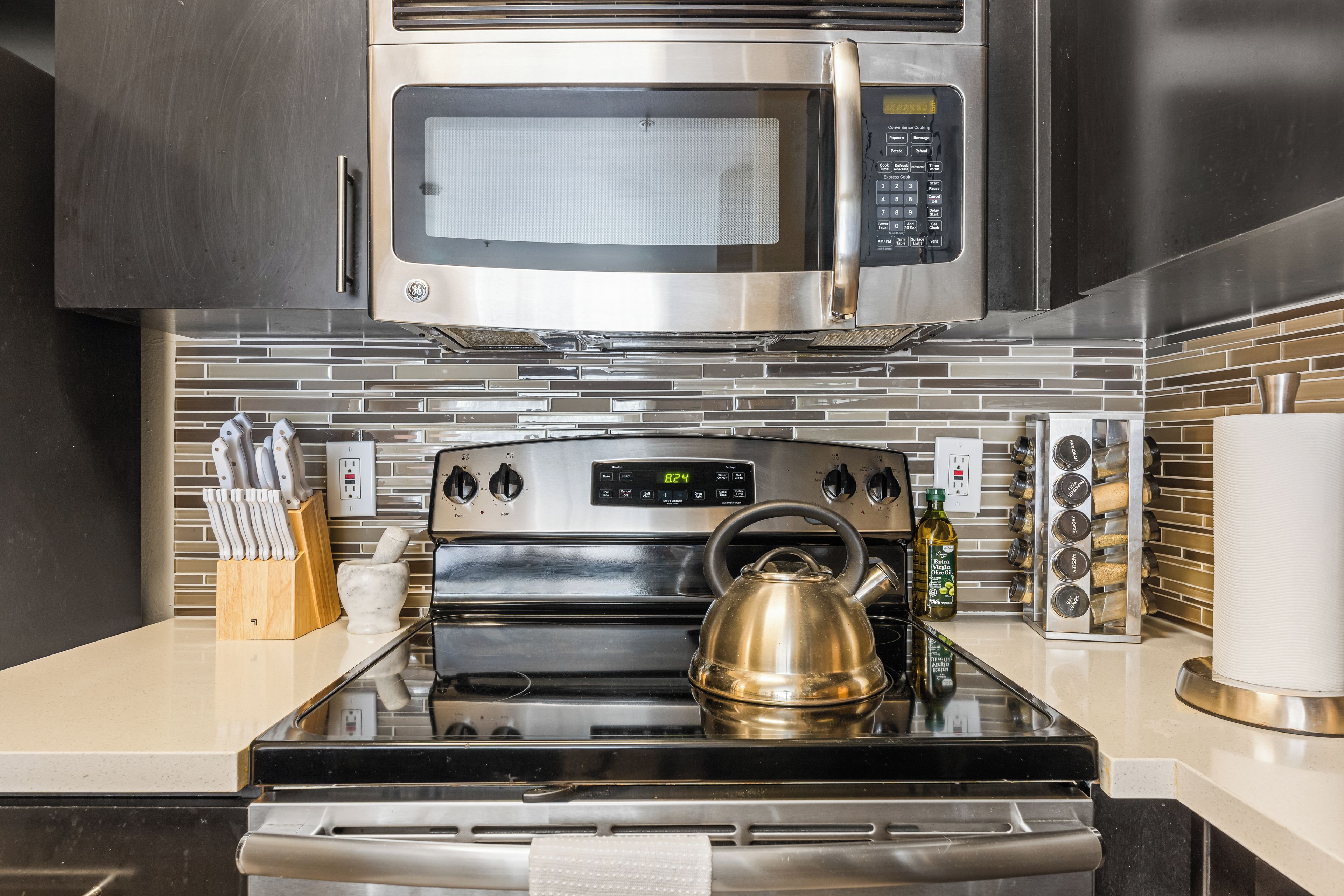 Eine Küche mit Mikrowelle, Backofen und Wasserkocher aus Edelstahl.