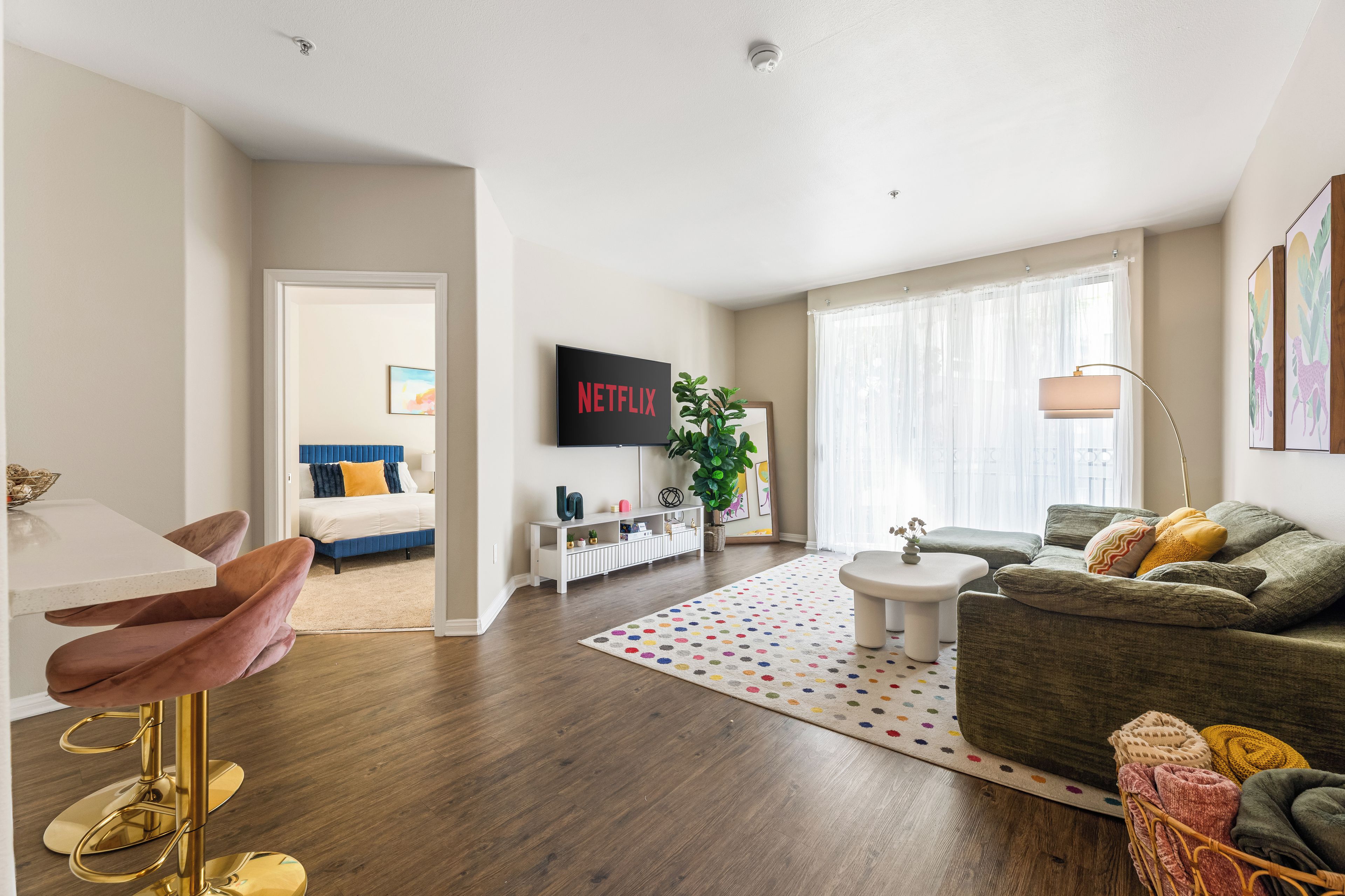 Ein modernes Wohnzimmer mit Flachbildfernseher, einer Couch, einem Couchtisch und einem Essbereich mit Stuhl und Tisch.