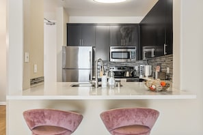 A modern kitchen with stainless steel appliances, a marble countertop, and a built-in oven. - Charming 2-bedroom apartment with pool, gym and free parking in Marina del Rey! (Marina del Rey)
