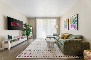 A living room with a sofa, coffee table, and a TV mounted on the wall. - Charming 2-bedroom apartment with pool, gym and free parking in Marina del Rey! (Marina del Rey)