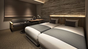 Ein Hotelzimmer mit einer Couch, einem kleinen Tisch mit einem Wasserkocher und einem Bett mit zwei Kissen.