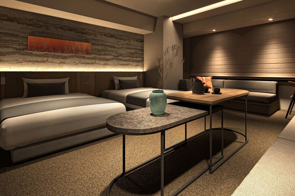 A modern hotel room with a sofa, a small table, and a decorative vase.