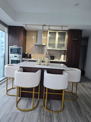 A modern kitchen with a central island, bar stools, and built-in appliances. - Toronto in the Sky | CN Tower & Lake Views (Toronto)