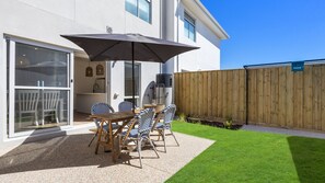 A patio with a table and chairs, a water heater, and a wooden fence. - Cormorant Retreat Family-Friendly Torquay Escape (Torquay)