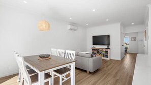 Un espacio moderno para vivir con comedor, sofá, televisor y estantería.