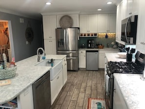 A modern kitchen with white cabinetry, stainless steel appliances, and a granite countertop. - Sand Lake Extended Stay Ranch - Fully Furnished Lake Home - Monthly Stays (Lindenhurst)
