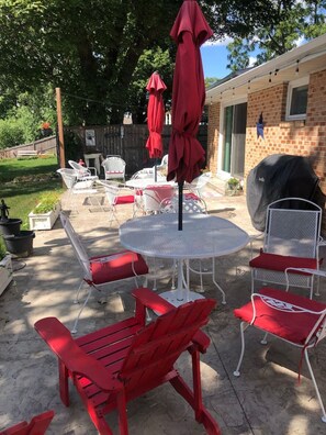 A patio with outdoor furniture, a barbecue grill, and a covered table with umbrellas. - Sand Lake Extended Stay Ranch - Fully Furnished Lake Home - Monthly Stays (Lindenhurst)