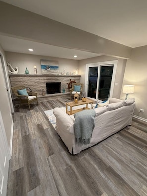 A living room with a fireplace, a sofa, and a coffee table. - Sand Lake Extended Stay Ranch - Fully Furnished Lake Home - Monthly Stays (Lindenhurst)