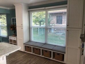 A kitchen with a built-in bench, storage baskets, and a window with blinds. - Sand Lake Extended Stay Ranch - Fully Furnished Lake Home - Monthly Stays (Lindenhurst)