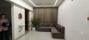 A modern living room with a sectional sofa, a potted plant, and a wall-mounted sink.