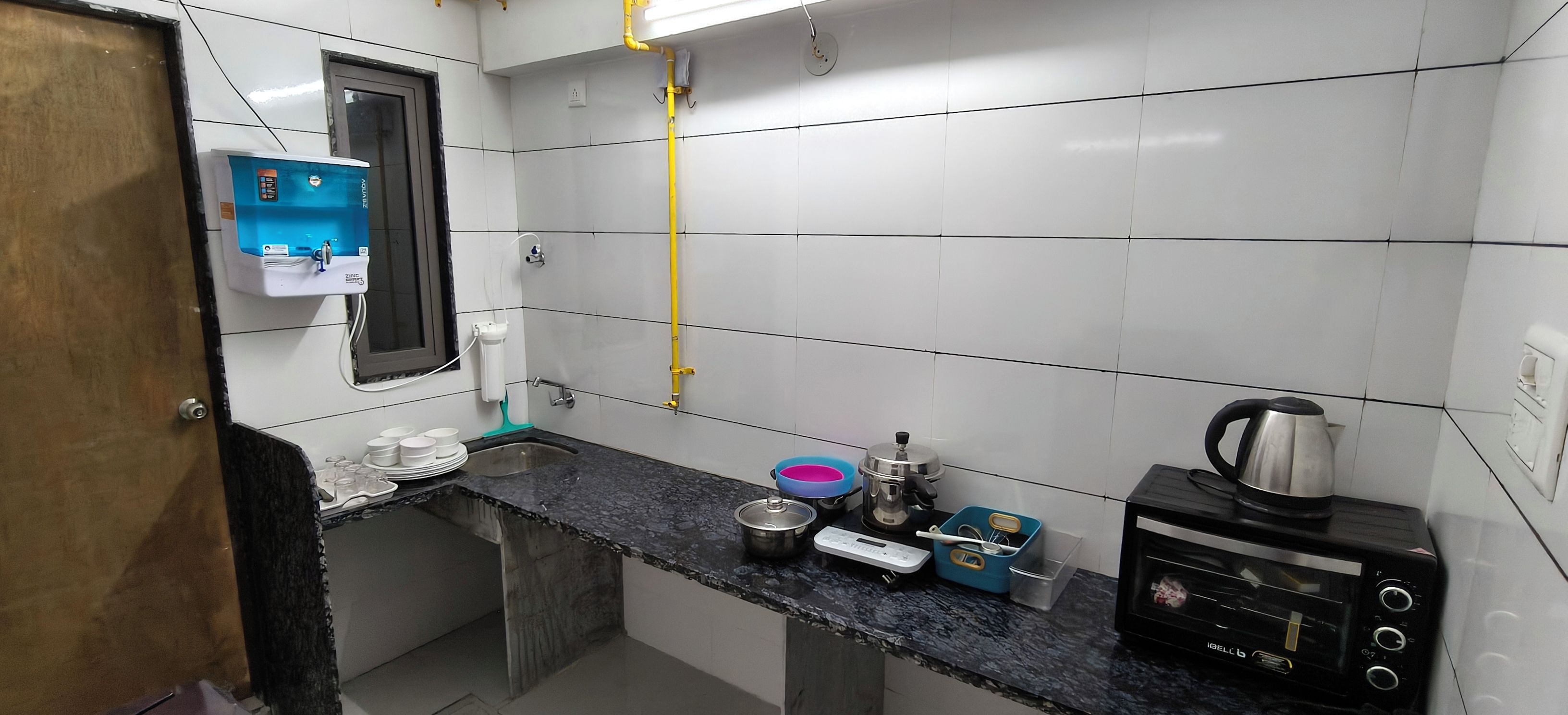 A compact kitchen with a sink, a coffee maker, a kettle, and a toaster.