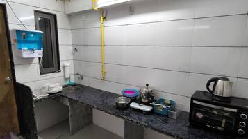 A compact kitchen with a sink, a coffee maker, a kettle, and a toaster.