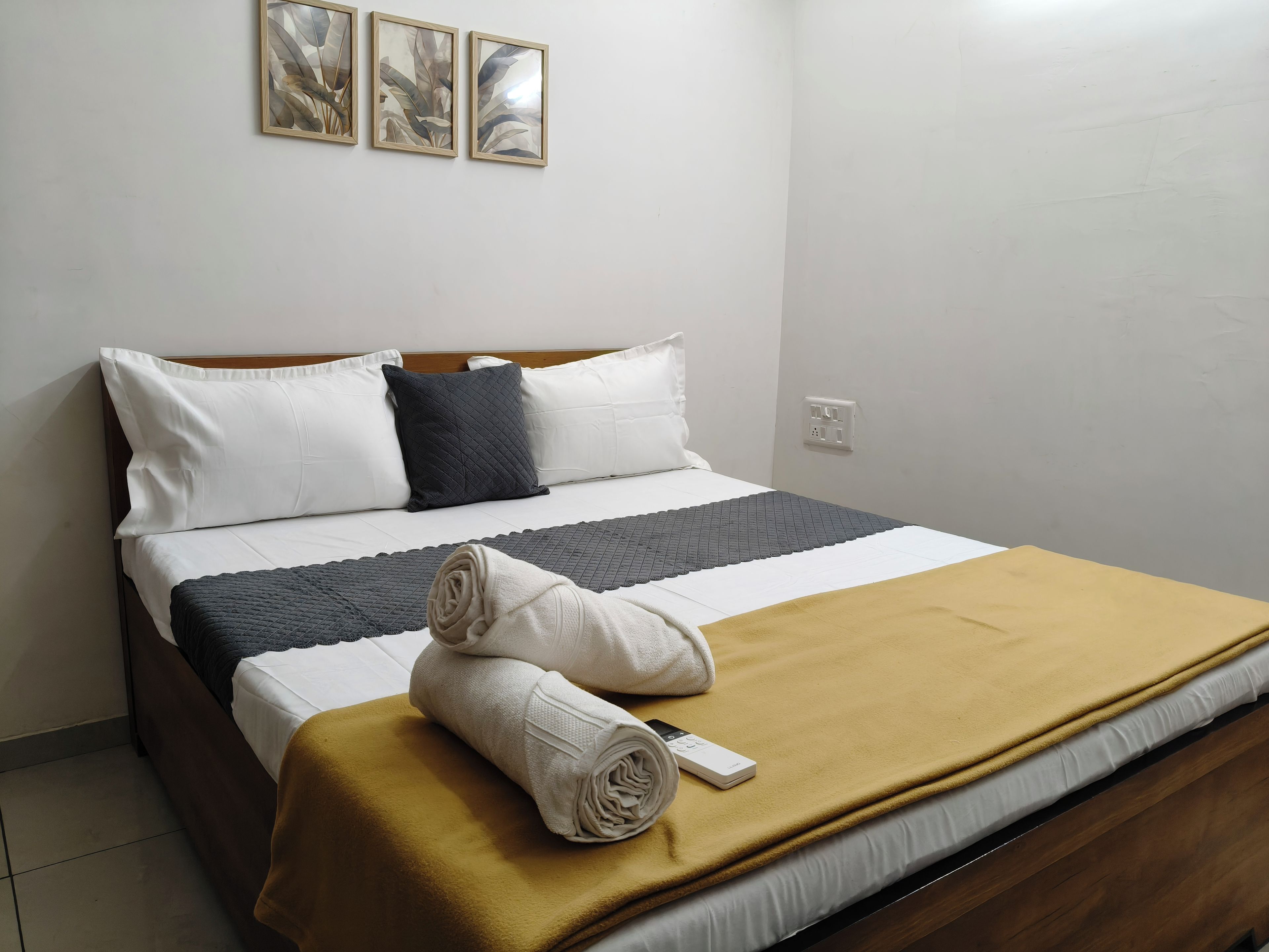 A neatly made bed with a brown blanket, white pillows, and a quilted bedspread.