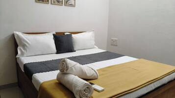 A neatly made bed with a brown blanket, white pillows, and a quilted bedspread.