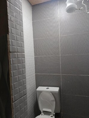 Ein Badezimmer mit Toilette, Dusche und Fliesen.