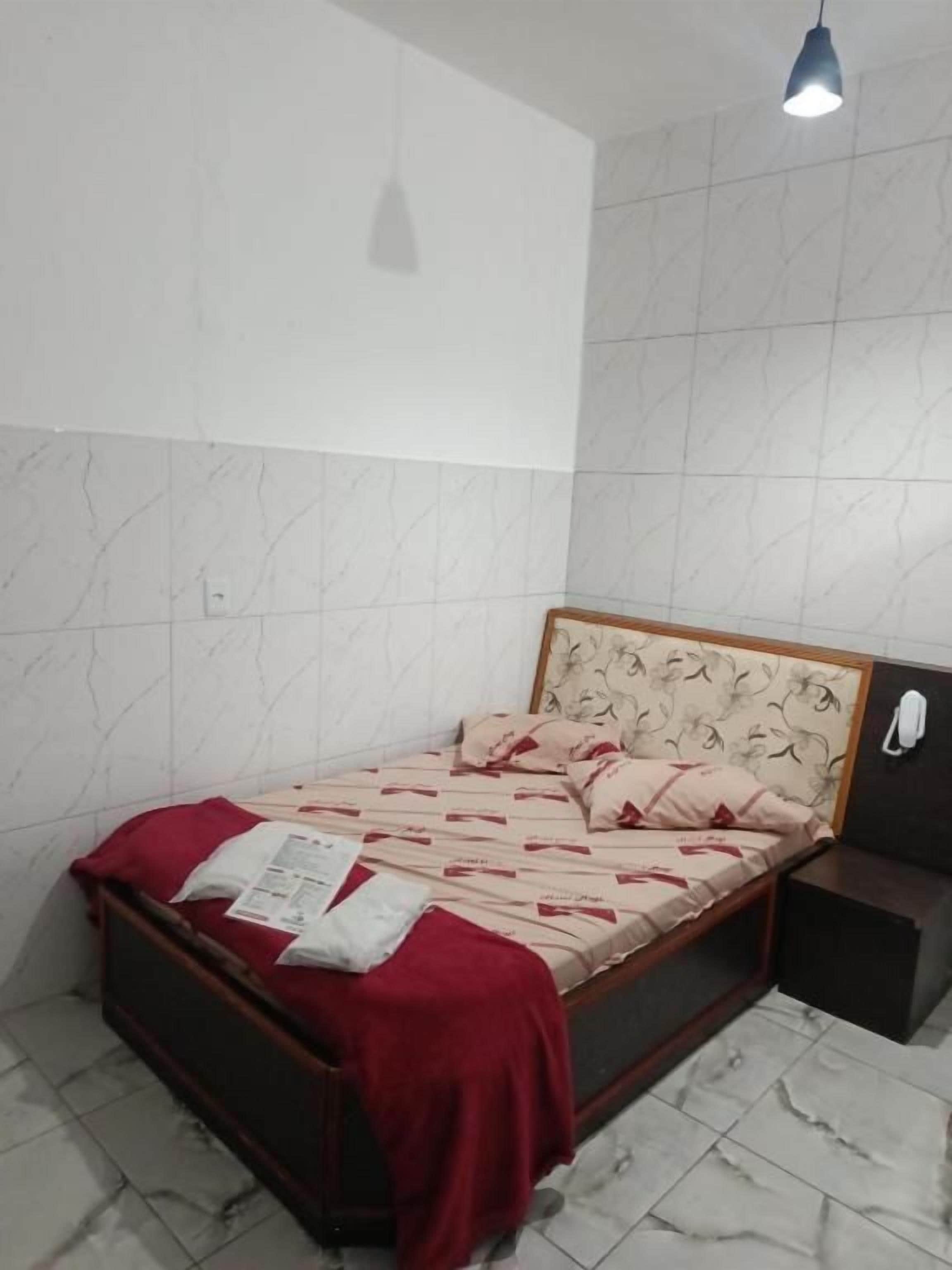 Une chambre à coucher avec un lit, une table de chevet, une lampe et un mur orné d’un motif.