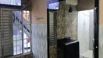 A bathroom with a stone wall, a tiled floor, a black sink, and a window with blinds.