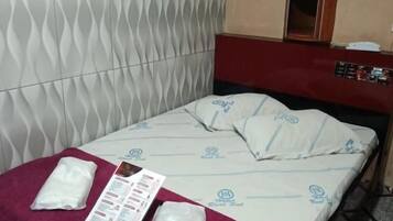 A hotel room with a bed, a red towel, a remote control, and a menu on the bed.