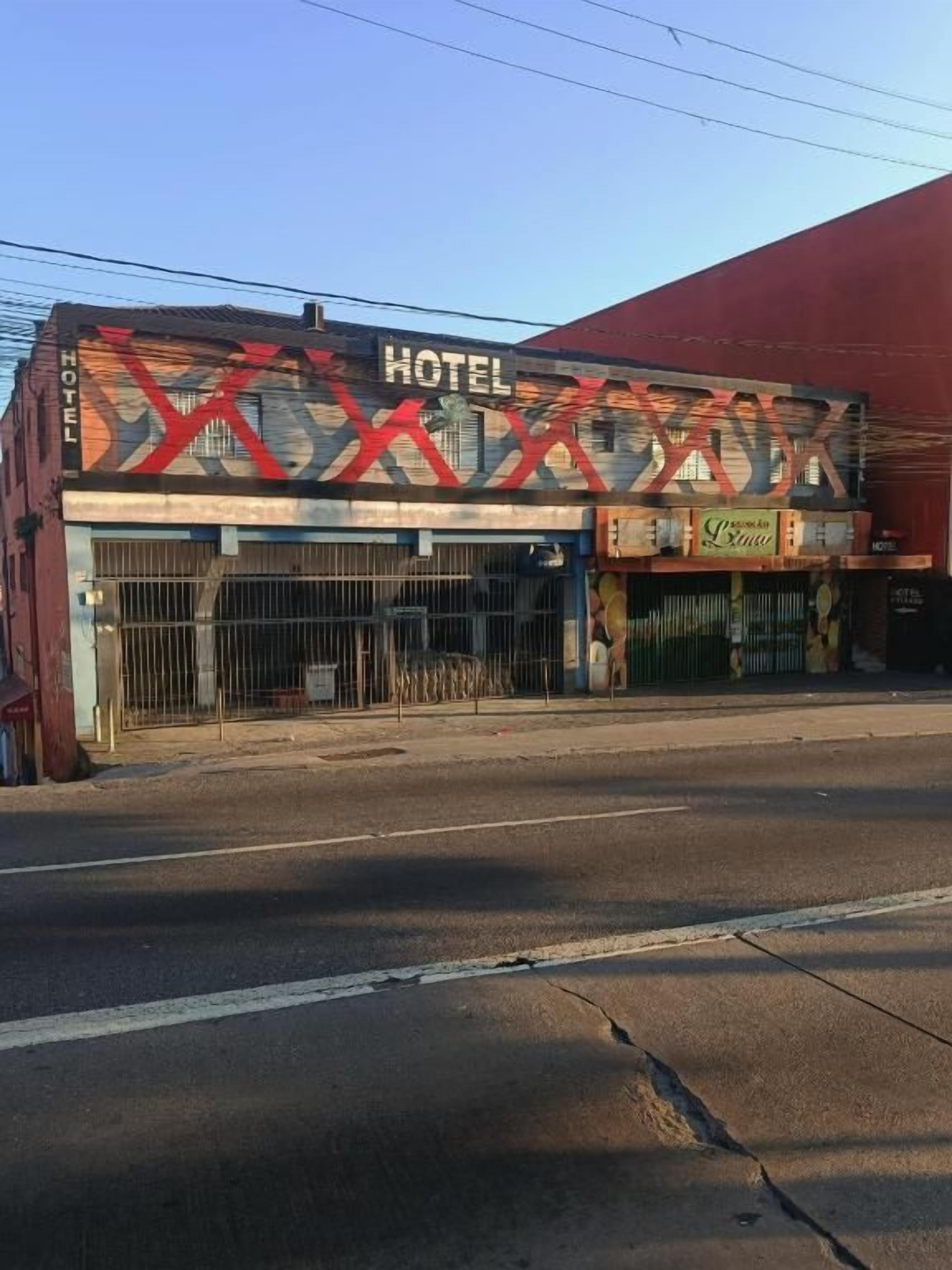 A hotel with a prominent sign, a gated entrance, and a red awning.